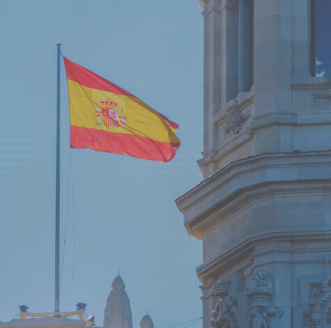 Drapeau espagnol flottant devant un bâtiment historique, symbolisant la formation en Espagnol certifiée LILATE à Cambrai