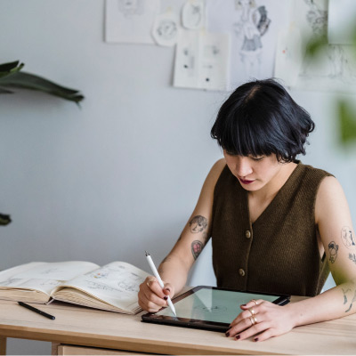 Jeune artiste féminine utilisant Adobe Illustrator sur une tablette graphique pour créer des illustrations numériques