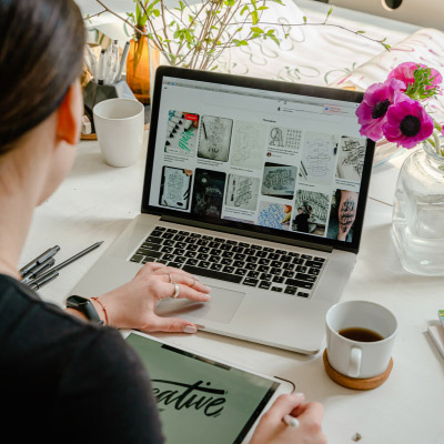 Femme travaillant sur Adobe InDesign depuis son bureau à domicile, créant des mises en page de design graphique