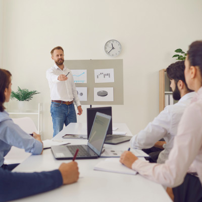 Formateur présentant des graphiques à un groupe de professionnels attentifs lors d'une session de formation en entreprise