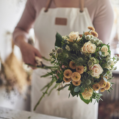 Fleuriste professionnelle préparant un bouquet de mariage élégant dans un atelier floral