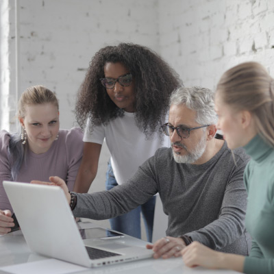 Groupe de professionnels diversifiés collaborant autour d'un ordinateur portable lors d'une session de management d'équipe