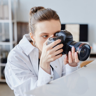 Photographe féminine concentrée ajustant son appareil photo reflex numérique pour capturer une image en mode manuel