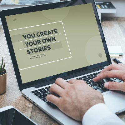Entrepreneur travaillant sur un ordinateur portable avec un écran affichant le message 'You Create Your Own Stories', soulignant l'esprit d'initiative en affaires