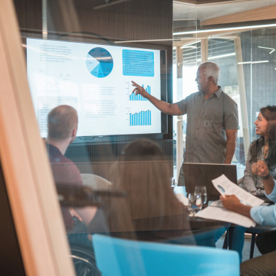 Formateur présentant des graphiques sur PowerPoint à un groupe de professionnels lors d'une session de formation en entreprise