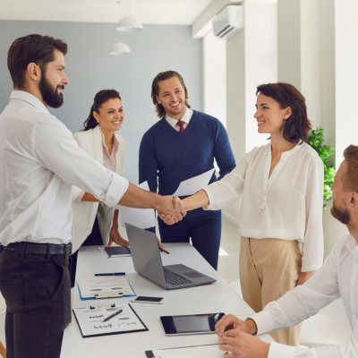 Professionnels souriants se serrant la main lors d'une réunion, symbolisant une négociation commerciale réussie