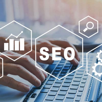 Mains travaillant sur un ordinateur portable avec des icônes SEO flottantes, symbolisant l'optimisation de site web